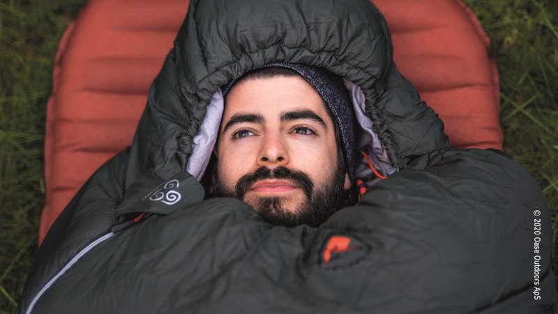 Man wrapped in a dark grey sleeping bag.